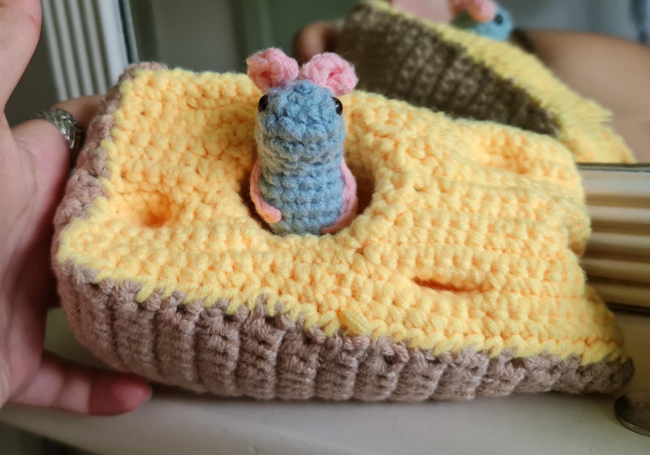 A crochet mouse poking out of a crochet cheese